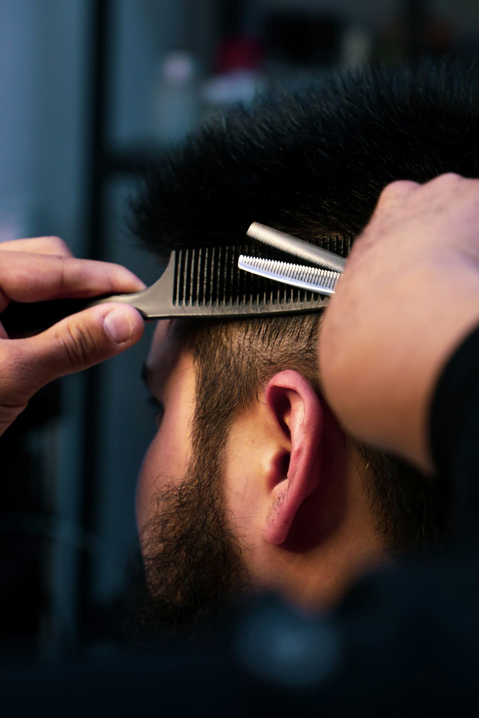 Barbeiro a aparar o cabelo de um cliente com pente e tesoura