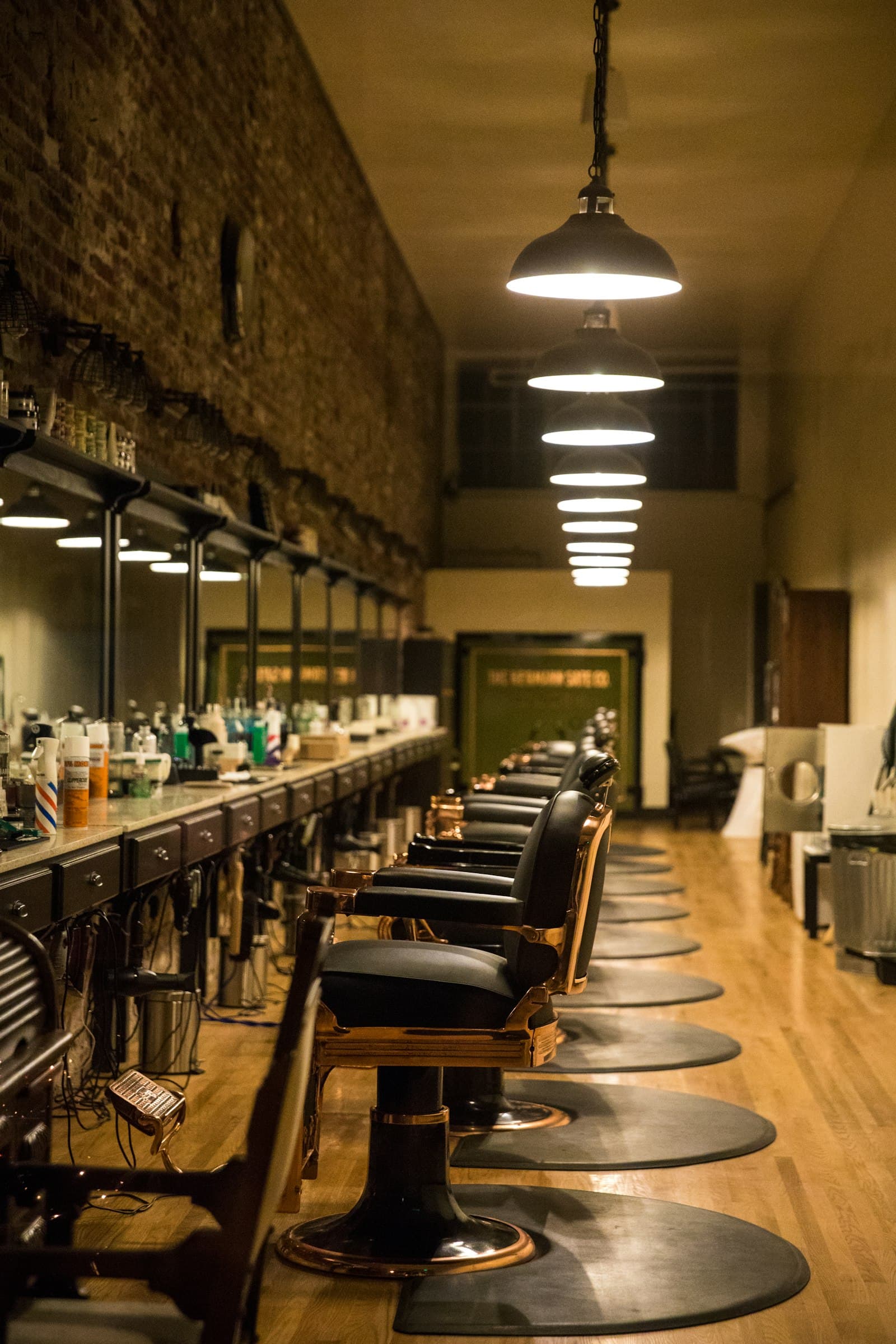 Interior de barbearia com cadeiras alinhadas e candeeiros suspensos